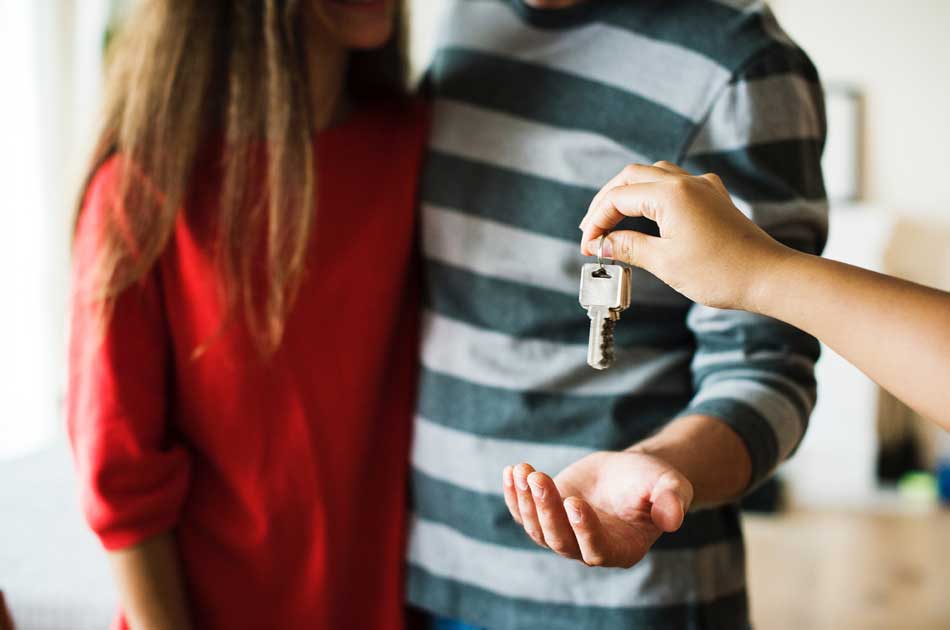 A couple receives the keys to their first home after deciding between a conventional or an FHA loan